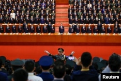 A conductor leads an orchestra as delegates stand for the national anthem during the closing session of the 19th National Congress of the Communist Party of China at the Great Hall of the People in Beijing, Oct. 24, 2017.