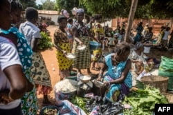 FILE - Food is offered to a vendor in exchange for her goods at the barter market in Togoville, Nov. 24, 2018.