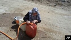 An Iraqi woman gathers water in a neighborhood in central Fallujah, Iraq as Iraqi counterterrorism forces battle Islamic State militants on the southern edge of the city on May 31, 2016.