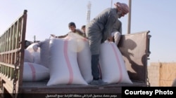 FILE - Sacks of processed corn are loaded on trucks outside Raqqa, Syria, Oct. 23, 2016. (Credit: Dawa al-Haq)