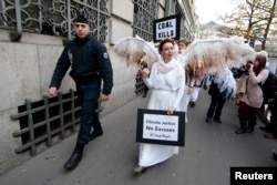 FILE - A French police officer escorts Australian environmental activists called Climate Guardian Angels during a demonstration as part of the World Climate Change Conference 2015 (COP21) in Paris, France, December 3, 2015.