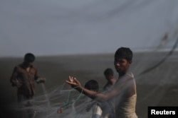 FILE - Rohingya refugees shake out fish from nets after the days catch on Shamlapur beach in Cox's Bazar, Bangladesh, March 21, 2018.