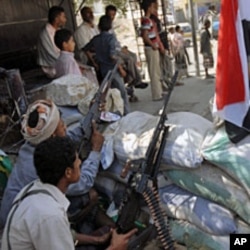 Tribal fighters backing protesters sit on alert behind sandbags during a demonstration to demand the trial of Yemen's outgoing President Ali Abdullah Saleh in the southern city of Taiz, December 5, 2011