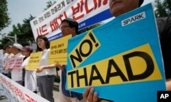 FILE - South Korean protesters hold signs during a rally to denounce deploying the Terminal High-Altitude Area Defense, or THAAD, in front of Defense Ministry in Seoul, South Korea, July 8, 2016.