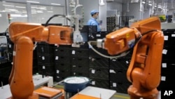FILE - A Chinese worker is seen behind robotic arms at a technology factory in Shenzhen, southern China, Aug. 21, 2015. China is spearheading a campaign for openness fearing that Chinese exporters could otherwise face stiffer resistance in Western countries.