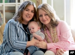 FILE - Cari Searcy, left, and Kim McKeand pose for a portrait with their son, Khaya, in Mobile, Ala., May 4, 2006.