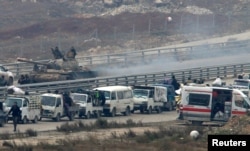 Forces loyal to Syria's President Bashar al-Assad sit on a tank as a convoy of buses and other vehicles bringing people out of eastern Aleppo turns back in the direction of the besieged rebel enclave, Syria, Dec. 16, 2016.