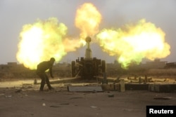 FILE - Popular Mobilization Forces fire toward Islamic State militants during a battle on the outskirts of Al-Ba'aj, west of Mosul, Iraq, May 26, 2017.