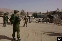 FILE - In this is image from video, Syrian government forces and Russian soldiers oversee the evacuation by buses of rebel fighters and their families, at a checkpoint in eastern Gouta, Syria, March, 22, 2108.