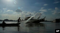 A fisherman casts his fishing net next to a ferry in the Mekong river near Phnom Penh, Cambodia, Tuesday, Dec. 1, 2015.