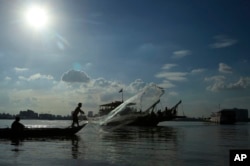 FILE - A fisherman casts his fishing net next to a ferry in the Mekong river near Phnom Penh, Cambodia, Tuesday, Dec. 1, 2015.