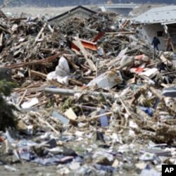 A survivor walks through debris in Rikuzentakata, Iwate prefecture, where the earthquake and tsunami hit last week, March 18, 2011
