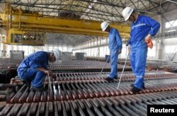 FILE - Workers inspect the production of copper cathodes at a Jinlong Copper plant in Tongling, Anhui province, China, Aug. 16, 2018.