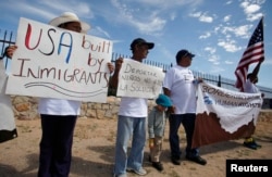 FILE - Mexican border residents and members of the Border Network for Human Rights (BNHR) hold up placards and a banner during a protest to reject border militarization and the deportation of children, outside a detention center in El Paso, Texas, Aug. 24