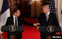 French President Emmanuel Macron reaches out to U.S. President Donald Trump as he speaks during their joint news conference at the White House in Washington, April 24, 2018.