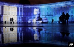 People look at a portrait of the last Russian Czar, Nicholas II, drawn in light at Dvortsovaya (Palace) Square during a light show marking the centenary of the Bolshevik Revolution in St.Petersburg, Nov. 4, 2017.