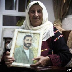 Zahra Falana sits at her home with a picture of her son, Ata Falana, who was relocated to Gaza after being released October 18, 2011.