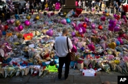 A man stands next to flowers for the victims of Monday's bombing at St Ann's Square in central Manchester, England, May 26 2017.