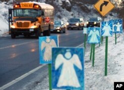 FILE - In this Jan. 3, 2013, file photo, a bus traveling from Newtown, Conn., to Monroe stops near 26 angel signs posted along the roadside in Monroe, Conn., on the first day of classes for Sandy Hook Elementary School students.