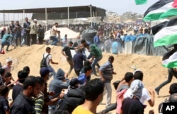 Palestinian protesters run for cover from teargas fired by Israeli troops near the Israeli border fence, east of Khan Younis, in the Gaza Strip, May 14, 2018.