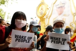 Pro-democracy protesters holding signs walk past a picture of Thai King Maha Vajiralongkorn during a rally near the Democracy Monument in Bangkok, Thailand, August 16, 2020.