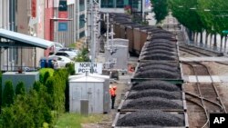 FILE - A train hauling coal runs between office buildings, condos and the downtown waterfront in Seattle, Washington. Scientific consensus holds that the emission of greenhouse gases from the burning of fossil fuels is the main cause of global warming.