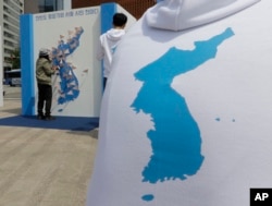 A woman puts a sign bearing messages wishing for peace in the two Koreas on a map of the Korean Peninsula in Seoul, South Korea, April 26, 2018.