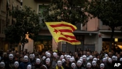 People wear white masks in support of Catalonian politicians jailed on charges of sedition and condemning the arrest of Catalonia's former president, Carles Puigdemont, in Germany, during a protest in Figures, Spain, April 5, 2018.