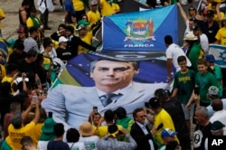 People hold a banner with a photo of Brazil's former army captain Jair Bolsonaro before the swearing-in ceremony, in front of the Planalto palace in Brasilia, Jan. 1, 2019.