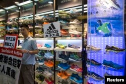 A labor activist stands outside an Adidas store with a protest sign, in support of a strike by workers of Yue Yuen Industrial Holdings, pasted on its shop window during International Labour Day in Hong Kong May 1, 2014.