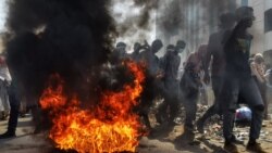 Sudanese protesters rallying against the military walk past burning tires in Khartoum, Jan. 6, 2022. The protests followed the resignation of civilian Prime Minister Abdalla Hamdok this week, which left the military fully in charge.