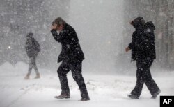 Pedestrians cross the street in downtown Boston, Jan. 4, 2018. A massive winter storm swept from the Carolinas to Maine on Thursday, dumping snow along the coast and bringing strong winds that will usher in possible record-breaking cold.