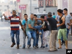 Palestinians carry an injured man during an Israeli military raid in the West Bank city of Jenin, Oct. 4, 2015.