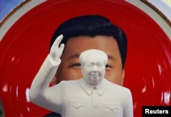 资料照片：北京天安门附近一个纪念品商店里毛泽东的塑像摆在习近平纪念画盘的前面。（2018年3月1日）