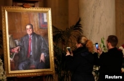 A couple takes photographs of a painting of late U.S. Supreme Court Justice Antonin Scalia in the Great Hall of the Supreme Court in Washington, Feb. 19, 2016.