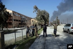 Iraqi Federal policemen celebrate while standing between the liberated airport and sugar plant in western Mosul, Iraq, Feb. 24. 2017.