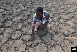 Last Zimaniwa feels the broken ground at a spot which is usually a reliable water source that has dried up due to lack of rains in the village of Chivi , Zimbabwe, Jan. 29, 2016.