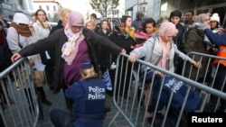 FILE - Residents of Molenbeek are searched by police before taking part in a memorial for the victims of the deadly Paris attacks, Nov. 18, 2015.
