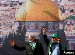 Hamas Chief Ismail Haniyeh and Gaza's Hamas Chief Yehya Al-Sinwar gesture to supporters during a rally marking the 30th anniversary of Hamas' founding, in Gaza City, Dec. 14, 2017. Al Aqsa mosque is in the background.