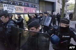 A migrant' supporter raises his hands as a policeman escorts him during a protest against the Jean-Jaurès highschool evacuation in Paris on May 4, 2016.