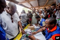 Ghana Incumbent President, John Dramani Mahama candidate of the National Democratic Congress, second left, validates his name before casting his vote during the Presidential and parliamentary election, in Bole Ghana, Dec. 7, 2016.