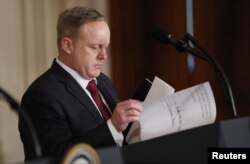 White House Press Secretary Sean Spicer goes through papers on the podium for President Donald Trump before a joint news conference with Israeli Prime Minister Benjamin Netanyahu.