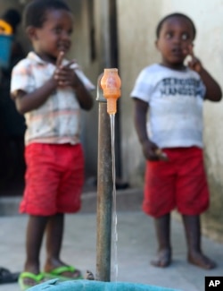 Children wait to fill up a bucket from a tap in a neighborhood in Beira, Mozambique, April, 2, 2019.