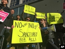 FILE - Protesters hold up signs outside a courthouse where a federal judge hears arguments in a lawsuit challenging President Donald Trump's executive order to withhold funding from communities that limit cooperation with immigration authorities, in San Francisco.