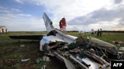People pose on July 14, 2014, standing on the wreckage of a Ukrainian AN-26 military transport plane after it was shot down by a missile, in the village of Davydo-Mykilske, east of Luhansk near the Russian border.