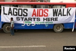 FILE - A man walks past a banner tied on a bus before the start of a charity walk on HIV/AIDS at the Ebute Mata district in Nigeria's commercial capital Lagos, April 21, 2012.