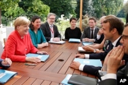 French President Emmanuel Macron, right, meets German Chancellor Angela Merkel at the Elysee Palace in Paris, Aug.28, 2017.