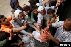 FILE - People gather to collect food rations at a food distribution center in Sana'a, Yemen, March 21, 2017.