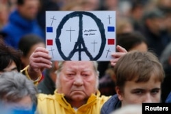 People observe a minute of silence in tribute to victims of Friday's attacks in Paris in front of French embassy, near the Brandenburg Gate in Berlin, Germany, Nov. 16, 2015.