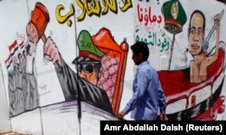 A member of the Muslim Brotherhood and supporter of ousted Egyptian President Mohamed Morsi walks in front of graffiti depicting Abdel Fattah al-Sisi, army commander and defense minister, around Cairo University and Nahdet Misr Square in Giza July 23, 201